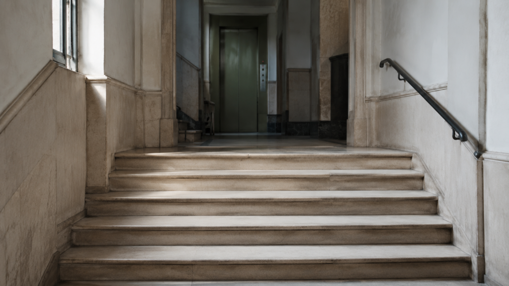 Portal de una comunidad de propietarios con varios escalones antes del ascensor.